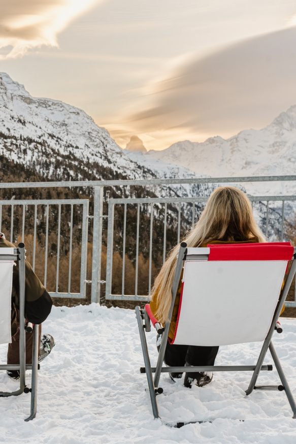 Zwei Personen auf Liegestühlen mit Blick auf die Berge